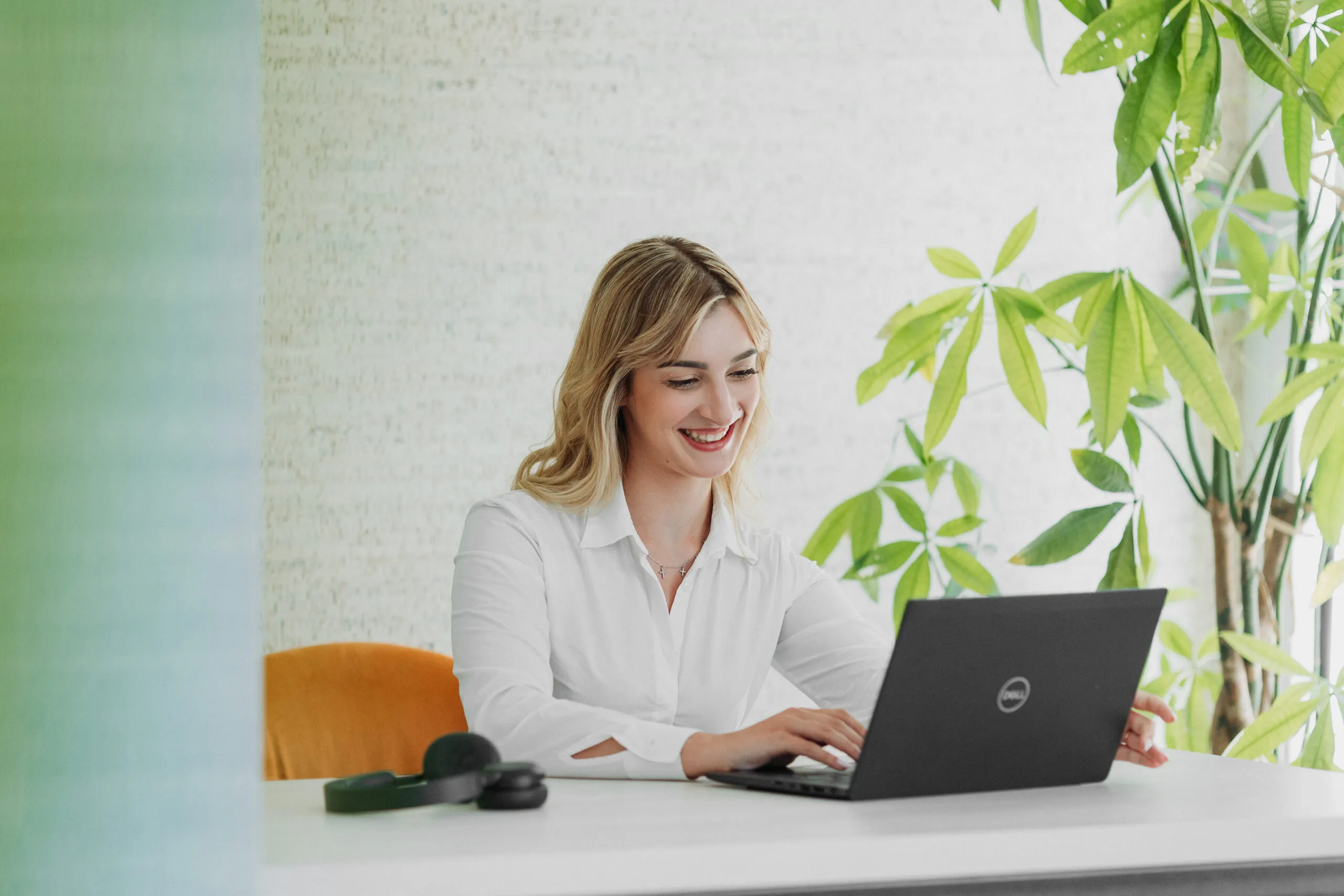 Miruna working at a bright desk beside a large green plant