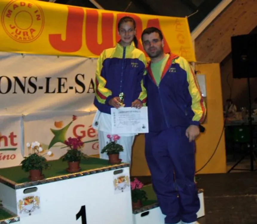 Miruna and her coach, holding a trophy and certificate after a karate competition
