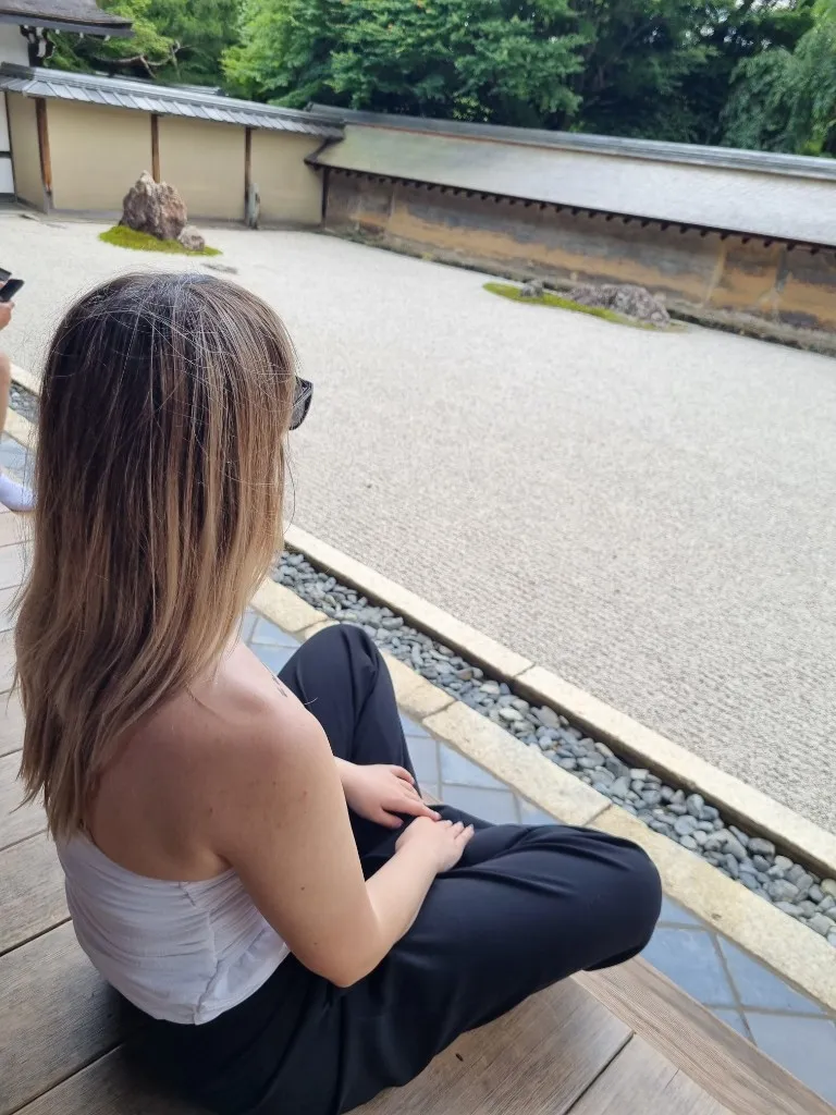 Miruna Zamfiriu sitting on a wooden veranda at Kongobu-ji Temple in Japan, looking out over a zen garden